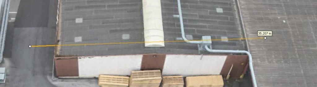 Drohnenbasiertes 3D-Modell einer Industriehalle mit präziser Längenmessung von 35,207 Metern entlang der Dachkante im RTK-Digitalen Zwilling