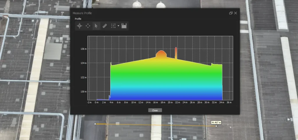 Farbcodiertes Höhenprofil einer Industriehalle als Querschnitt entlang der orange markierten Messlinie im RTK-basierten Digitalen Zwilling, inklusive Dachneigung, Firsthöhe und Aufbauten.